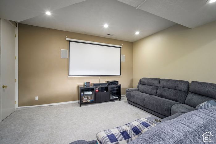 Theater room with a large projection screen, in-wall speakers, and a sectional sofa