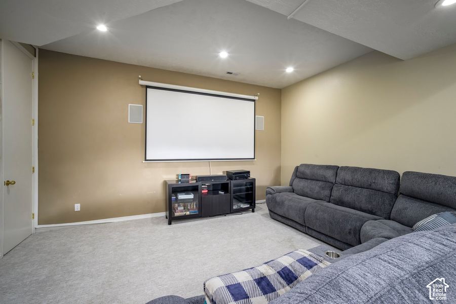 Theater room with a large projection screen, in-wall speakers, and a sectional sofa